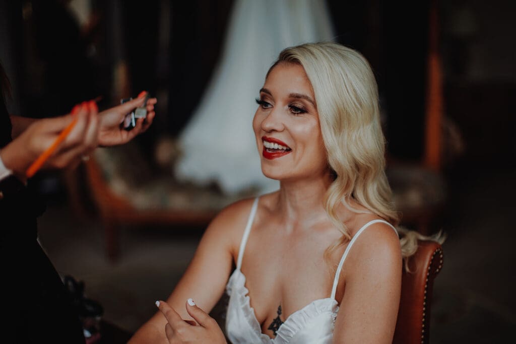 A bride laughing as she gets her makeup done