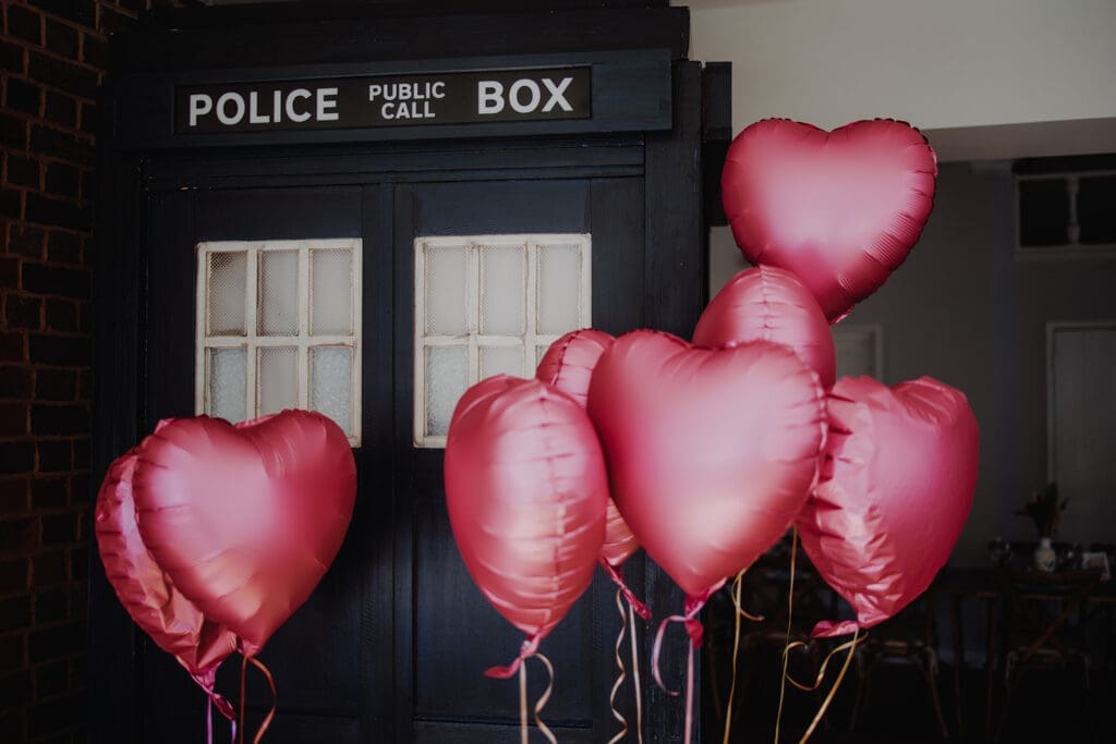 A blue Dr Who Police Box with bright pink heart balloons in front of it - fun wedding decor!