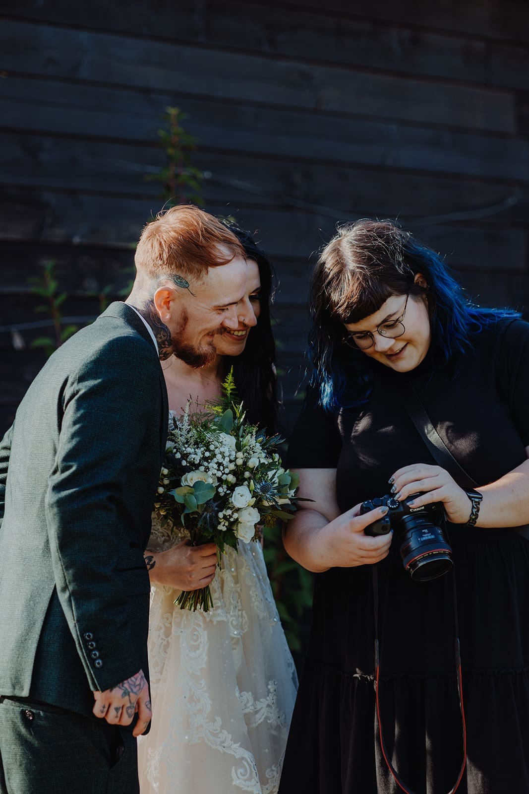 Katie the photographer at Alt Wedding Co showing the newlyweds a sneaky preview of their photos on her camera