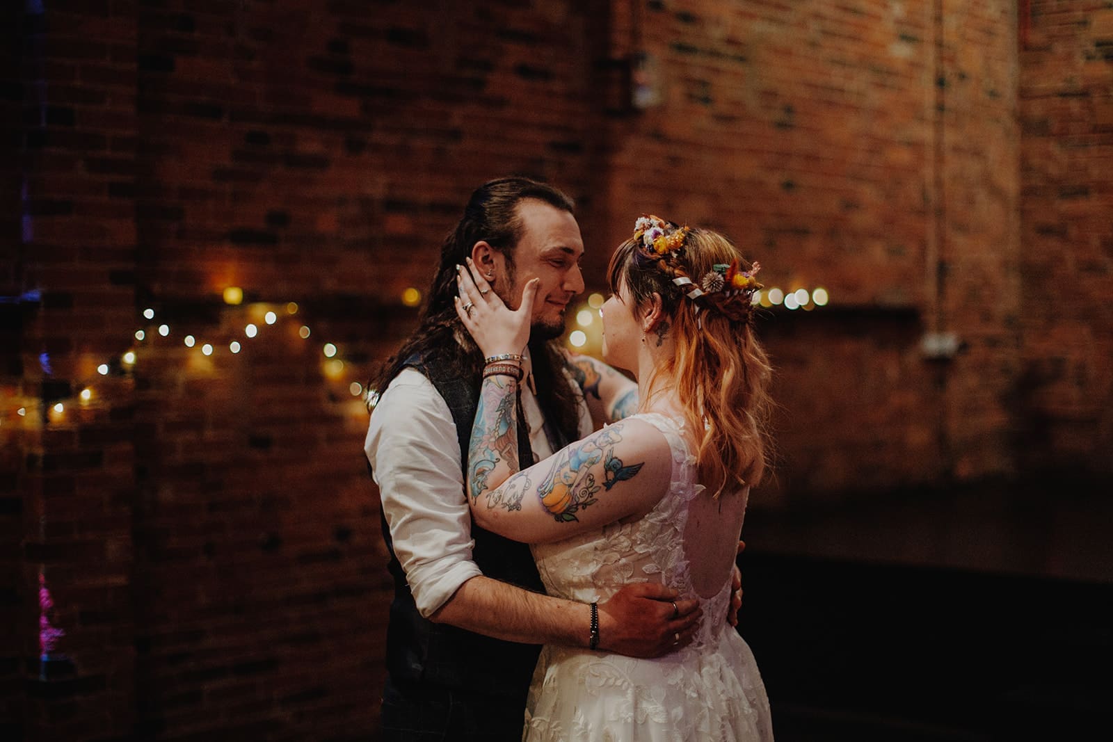 Newlyweds having their first dance - the bride is holding the groom's face in a loving embrace.