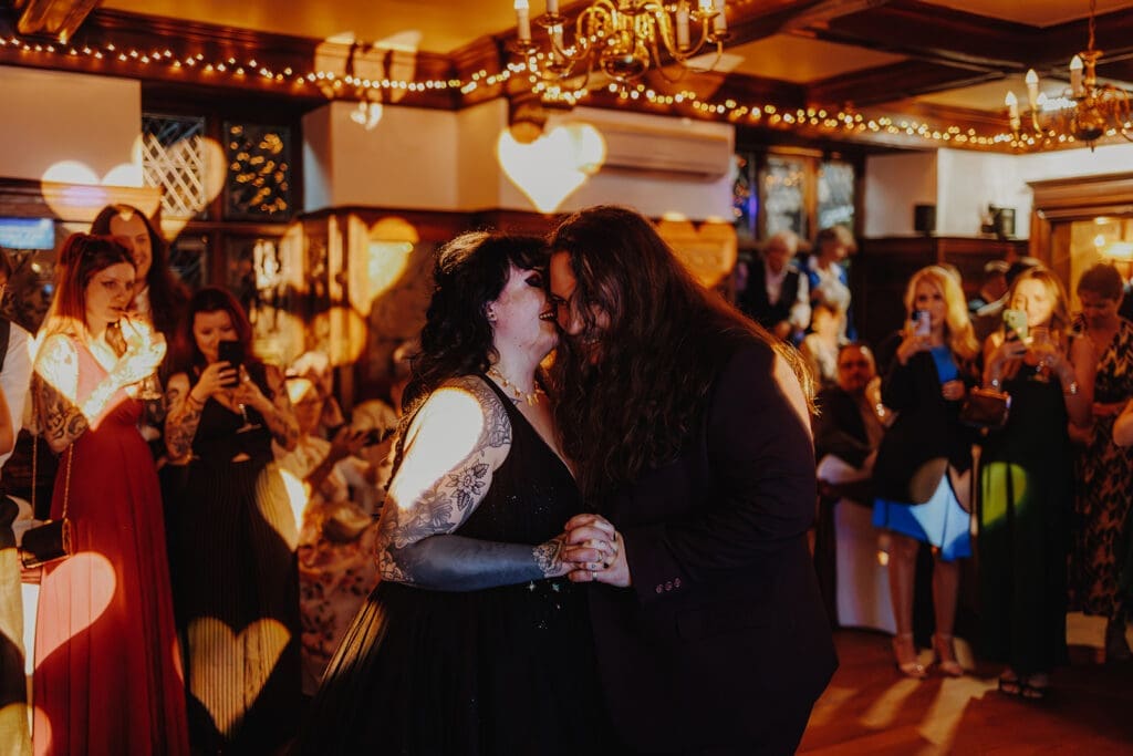 Newlyweds embrace on the dancefloor as love heart shaped lights fall on them. 